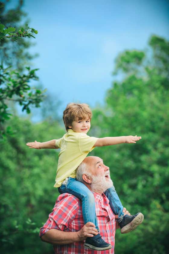 dziadek niesie siedzącego na jego ramionach chłopca